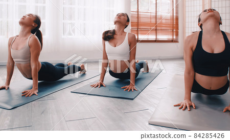 Group of Asian women stretching in yoga class. Group of girls doing Pilates exercises at the gym. 84285426
