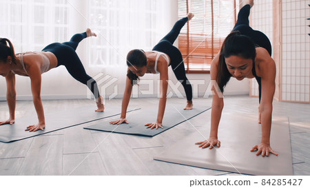 Group of Asian women stretching in yoga class. Group of girls doing Pilates exercises at the gym. 84285427
