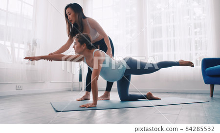 Pregnant woman doing Pilates exercise with personal trainer at home. 84285532