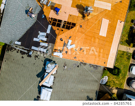 A worker replace shingles on the roof of a home repairing the roof of home A worker replace shingles on the roof of a home repairing the roof of home 84285761