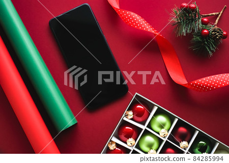 Christmas phone app and holiday message concept. Smartphone with blank black screen and xmas decoration on red background as flat lay mockup design 84285994