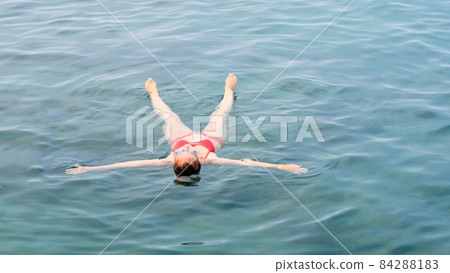 female in glasses lies a star on the sea, trains to maintain balance on the water, relaxation 84288183