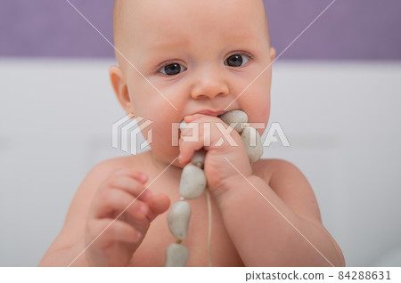 Baby boy gnaws wooden teething boxes. Eco friendly toy. Baby boy gnaws wooden teething boxes. Eco friendly toy. 84288631