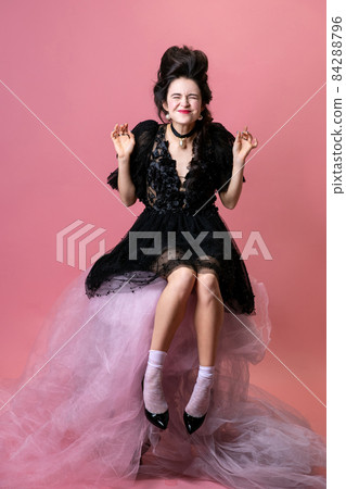 Portrait of young beautiful woman in black evening little dress isolated on pink background. Concept of holiday, fashion, style Portrait of young beautiful woman in black evening little dress isolated on pink background. Concept of holiday, fashion, style 84288796