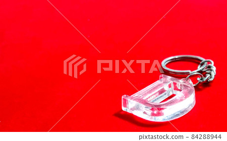 Close-up shot of a trinket with the capital letter "D" isolated on a red background 84288944