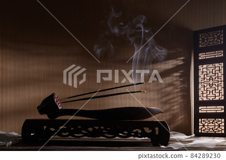 Smoke from burning incense sticks standing on lotus incense holder Smoke from burning incense sticks standing on lotus incense holder 84289230
