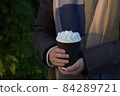 Young girl wearing woolly scarf holds a takeaway hot chocolate 84289721