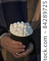 Close up vertical image of young woman warming hands on fancy hot drink 84289725