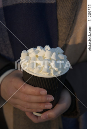 Close up vertical image of young woman warming hands on fancy hot drink Close up vertical image of young woman warming hands on fancy hot drink 84289725