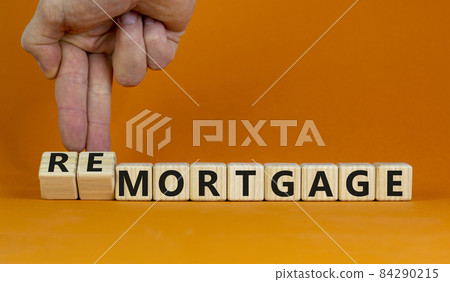 Hand turns cubes and changes the word 'remortgage' to 'mortgage' or vice versa. Beautiful orange background, copy space. Business concept. Hand turns cubes and changes the word 'remortgage' to 'mortgage' or vice versa. Beautiful orange background, copy space. Business concept. 84290215
