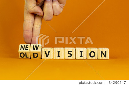 New or old vision symbol. Businessman turns cubes and changes words 'old vision' to 'new vision'. Beautiful orange table, orange background, copy space. Business, old or new vision concept. New or old vision symbol. Businessman turns cubes and changes words 'old vision' to 'new vision'. Beautiful orange table, orange background, copy space. Business, old or new vision concept. 84290247