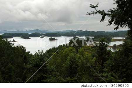 Qiandao Hu, Zhejiang Province, China: View of the lake and islands under a dramatic sky with foreground forest. Qiandao Hu translates as Thousand Island Lake and is a reservoir near Hangzhou. 84290805