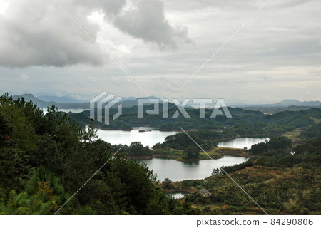 Qiandao Hu, Zhejiang Province, China: View of the lake and islands under a dramatic sky with foreground forest. Qiandao Hu translates as Thousand Island Lake and is a reservoir near Hangzhou. 84290806