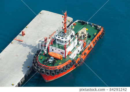 Tug boat with  bright red hull and green deck 84291242