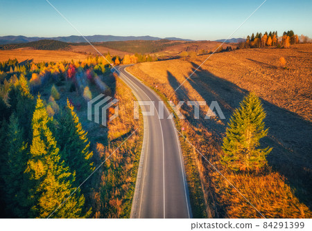 Aerial view of mountain road in forest at sunset in autumn Aerial view of mountain road in forest at sunset in autumn 84291399