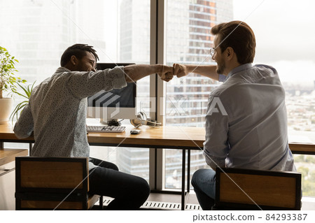 Happy two mixed race male colleagues bumping fists. Happy two mixed race male colleagues bumping fists. 84293387