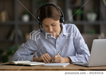Woman wear headset noting while studying use videocall on laptop 84293416