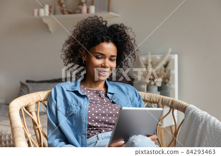Happy young woman reading book, ebook on tablet at home 84293463
