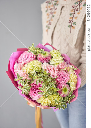 Beautiful bouquet of mixed flowers in woman hand. Handsome fresh bouquet. Small flower shop and Flowers delivery. 84294012