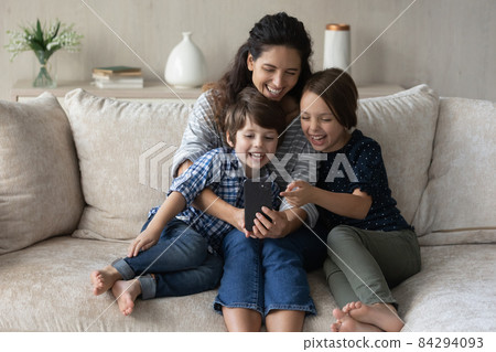Mom and kids look at cellphone screen and laughing 84294093
