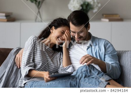 Happy man and laughing woman hugging, using tablet together 84294184