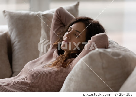 Close up peaceful woman with closed eyes resting on couch 84294193