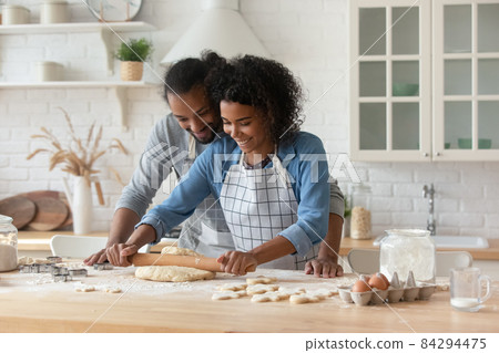 Happy young African couple wearing aprons cooking homemade bakery foods Happy young African couple wearing aprons cooking homemade bakery foods 84294475