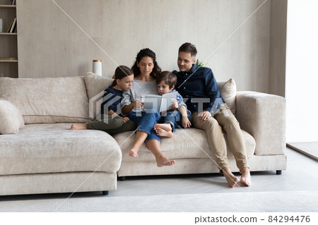 Couple with children sit on sofa enjoy fascinating fairytale book Couple with children sit on sofa enjoy fascinating fairytale book 84294476