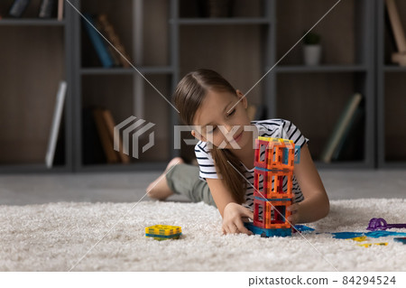 Little girl playing with colorful plastic blocks alone, building tower Little girl playing with colorful plastic blocks alone, building tower 84294524
