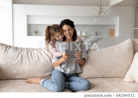 Smiling mother with cute daughter having fun with tablet together 84294551
