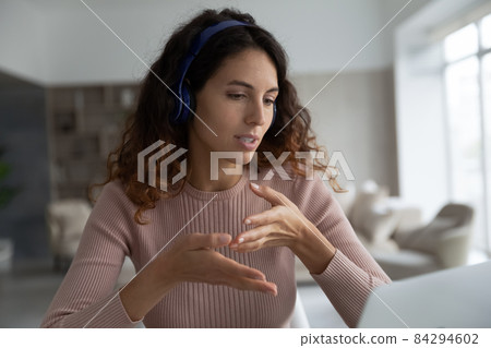 Close up confident businesswoman in headphones chatting online, using laptop 84294602