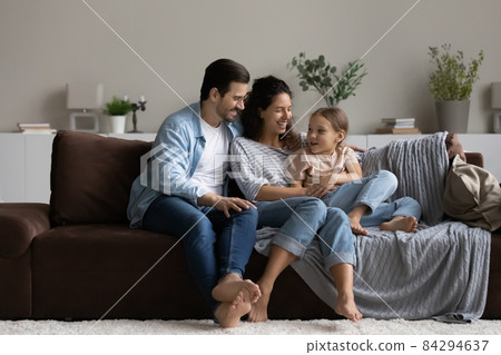 Happy parents with daughter relaxing on comfortable couch at home Happy parents with daughter relaxing on comfortable couch at home 84294637