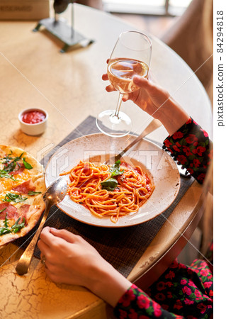 Woman eats Italian pasta with tomato, meat. Close-up spaghetti Bolognese wind it around a fork with a spoon. Parmesan cheese Woman eats Italian pasta with tomato, meat. Close-up spaghetti Bolognese wind it around a fork with a spoon. Parmesan cheese 84294818