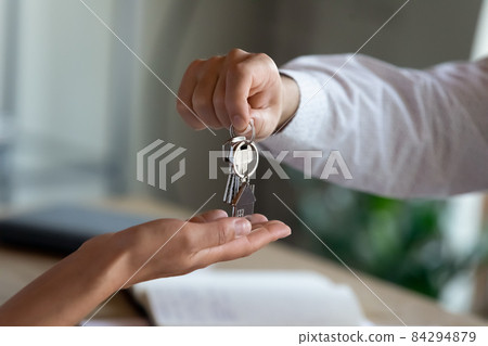 Close up professional realtor giving keys to client. 84294879