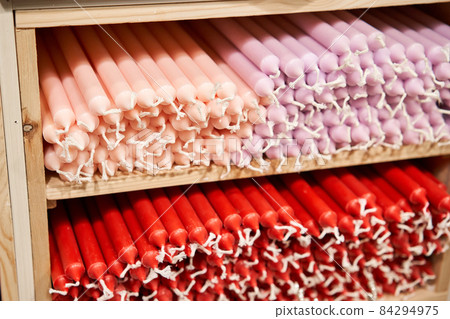 Many multicolored colorful paraffin stick Pastel colors candles arranged in shelves lying on shelter and sorted by color in a household candle shop store market. 84294975