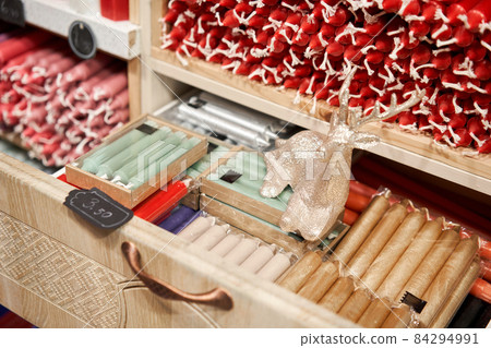Many multicolored colorful paraffin stick Pastel colors candles arranged in shelves lying on shelter and sorted by color in a household candle shop store market. Many multicolored colorful paraffin stick Pastel colors candles arranged in shelves lying on shelter and sorted by color in a household candle shop store market. 84294991