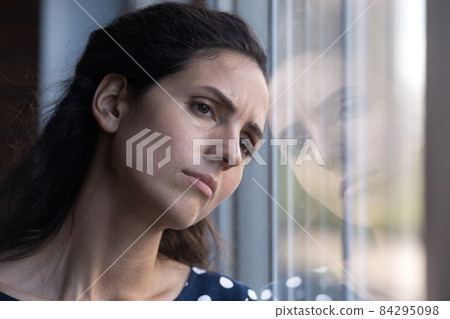 Sad millennial female pressing forehead against window suffer of divorce Sad millennial female pressing forehead against window suffer of divorce 84295098