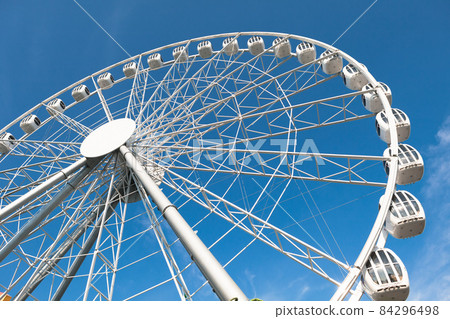 modern white ferris wheel against blue sky background 84296498