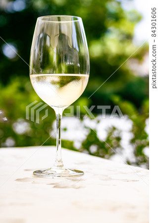 White wine in luxury restaurant on summer garden terrace, wine tasting experience at winery in the vineyard, gourmet tour and holiday travel White wine in luxury restaurant on summer garden terrace, wine tasting experience at winery in the vineyard, gourmet tour and holiday travel 84301606