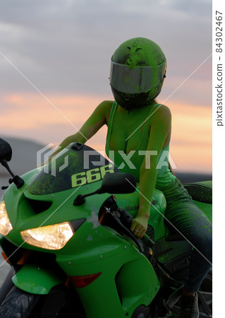 Unrecognizable woman on motorcycle at sunset 84302467