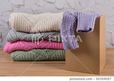 stack of folded sweaters on the table, one sweater in a box, internet commerce concept stack of folded sweaters on the table, one sweater in a box, internet commerce concept 84304097