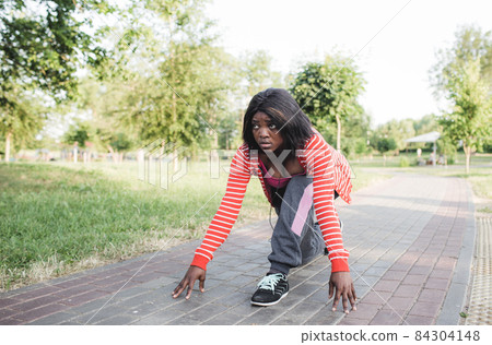 An African-American girl is getting ready for a run. low position to start. 84304148