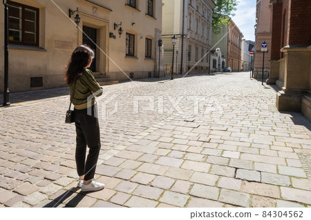 Woman standing and looking on empty street of old town Cracow Woman standing and looking on empty street of old town Cracow 84304562