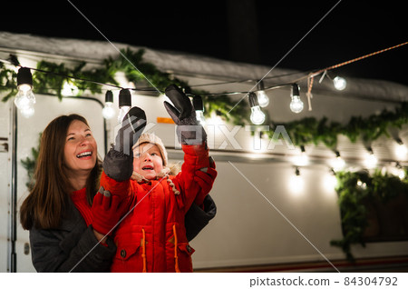 Caucasian woman and son decorate camper for christmas. Happy family travels in a mobile home. 84304792