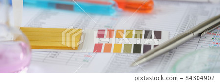 Test tubes with blue and orange liquid with test results on table Test tubes with blue and orange liquid with test results on table 84304902