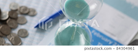 Hourglass calendar and coins lie on table closeup Hourglass calendar and coins lie on table closeup 84304961