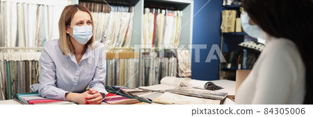 Seller consultant communicates with client wearing a protective medical mask and at safe distance Seller consultant communicates with client wearing a protective medical mask and at safe distance 84305006