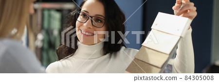 Smiling sales assistant shows samples with fabrics Smiling sales assistant shows samples with fabrics 84305008