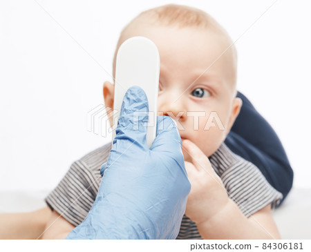 Pediatrician using infrared thermometer checking body temperature of baby boy Pediatrician using infrared thermometer checking body temperature of baby boy 84306181
