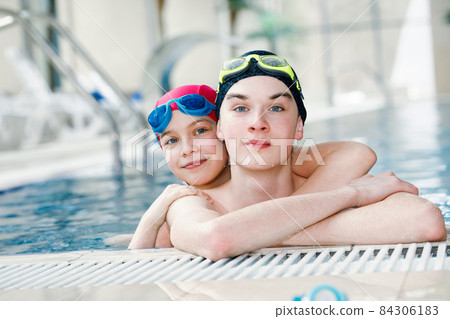 Siblings enjoying being in a swimming pool 84306183